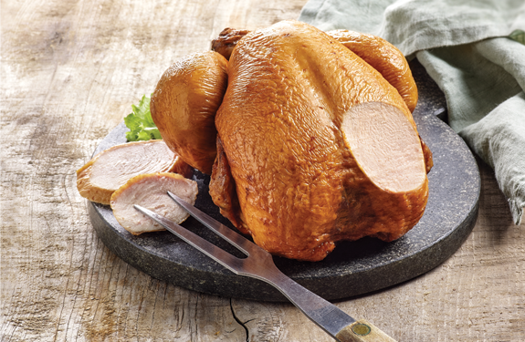 Pollo ahumado troceado y colocado en una tabla de cortar.